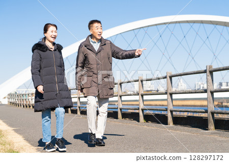 A middle-aged couple walking along a promenade 128297172