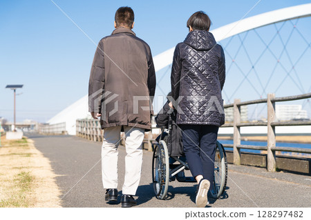 父母和孩子推著輪椅四處走動 父母和孩子推著輪椅四處走動 128297482