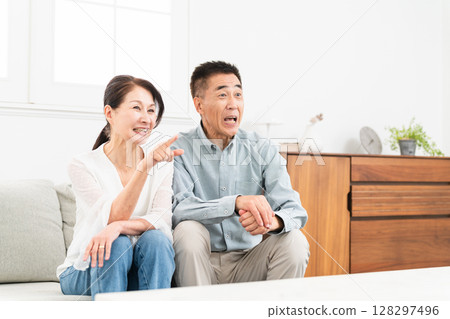 Mature couple sitting on sofa 128297496