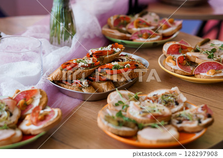 Rustic Bruschetta Platter with Tomatoes, Salami, and Herbs on Wooden Table. Vibrant Italian Appetizers, Indoor Dining Scene, Pink Hues 128297908