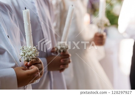 First Communion Candles Held by Children in White Outfits at Religious Ceremony, Bright Natural Light First Communion Candles Held by Children in White Outfits at Religious Ceremony, Bright Natural Light 128297927