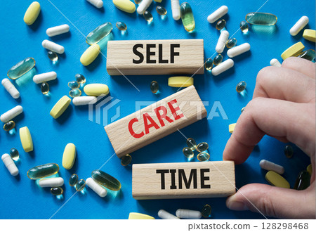 Self-care Time symbol. Concept words Self-care Time on wooden blocks. Beautiful blue background with pills. Doctor hand. Healthcare and Self-care Time concept. Copy space. 128298468