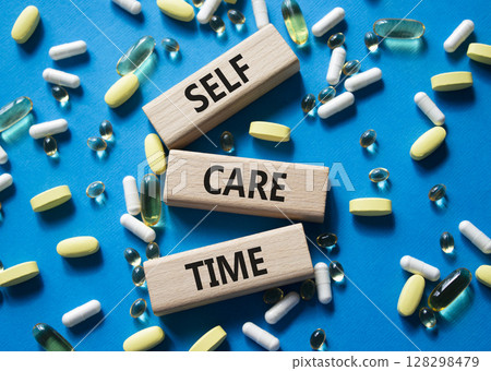 Self-care Time symbol. Concept words Self-care Time on wooden blocks. Beautiful blue background with pills. Healthcare and Self-care Time concept. Copy space. 128298479