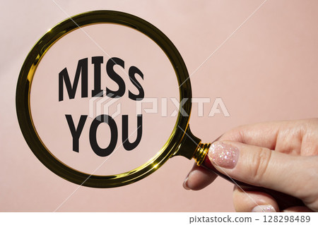 Miss you symbol. Magnifying Glass with Concept word Miss you. Beautiful pink background. Businessman hand. Miss you concept. Copy space 128298489