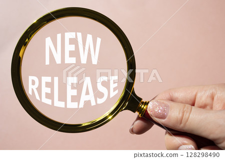New Release symbol. Concept word New Release on magnifying glass. Beautiful pink background. Businessman hand. Business and New Release concept. Copy space. 128298490