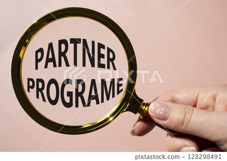 Partner Program symbol. Concept words Partner Program on magnifying glass. Businessman hand. Beautiful pink background. Business and Partner Program concept. Copy space. 128298491