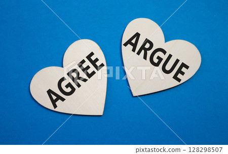 Agree or Argue symbol. Concept word Agree or Argue on wooden hearts. Beautiful blue background. Business and Agree or Argue concept. Copy space 128298507