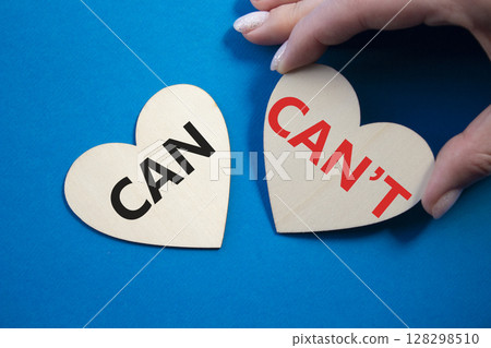 Can or Cant symbol. Concept word Can or Cant on wooden hearts. Businessman hand. Beautiful blue background. Business and Can or Cant concept. Copy space Can or Cant symbol. Concept word Can or Cant on wooden hearts. Businessman hand. Beautiful blue background. Business and Can or Cant concept. Copy space 128298510