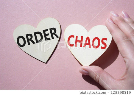 Chaos or Order symbol. Concept word Chaos or Order on wooden hearts. Businessman hand. Beautiful pink background. Business and Chaos or Order concept. Copy space Chaos or Order symbol. Concept word Chaos or Order on wooden hearts. Businessman hand. Beautiful pink background. Business and Chaos or Order concept. Copy space 128298519