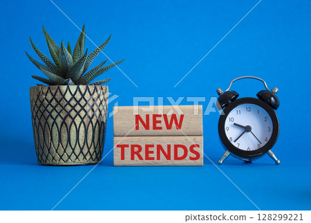 New Trends symbol. Wooden blocks with words New Trends. Beautiful blue background with alarm clock and succulent plant. Business and New Trends concept. Copy space. 128299221