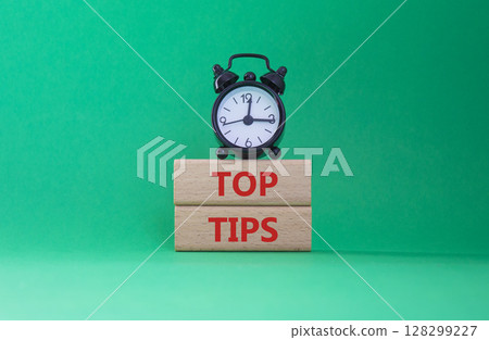 Top Tips symbol. Concept words Top Tips on wooden blocks. Beautiful green background with alarm clock. Business and Top Tips concept. Copy space. Top Tips symbol. Concept words Top Tips on wooden blocks. Beautiful green background with alarm clock. Business and Top Tips concept. Copy space. 128299227