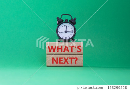 What is next symbol. Concept words What is next on wooden blocks. Beautiful green background with alarm clock. Business and What is next concept. Copy space. 128299228
