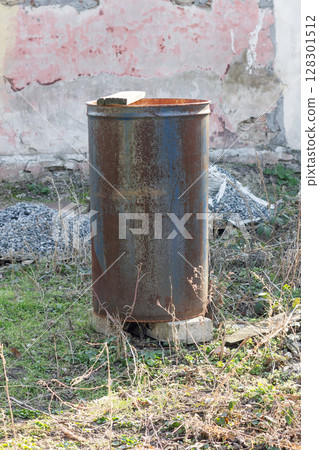 Rusty metal barrel in an abandoned outdoor setting. Rusty metal barrel in an abandoned outdoor setting. 128301512