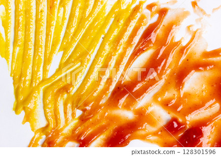 Close-up of mustard and ketchup smeared on a surface. Close-up of mustard and ketchup smeared on a surface. 128301596