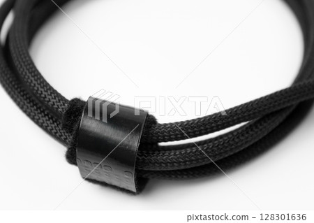 Close-up of black braided cable looped and secured with a band. 128301636