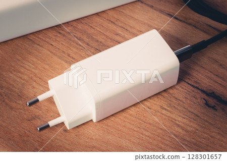 White electronic charger on wooden surface, closeup view. White electronic charger on wooden surface, closeup view. 128301657