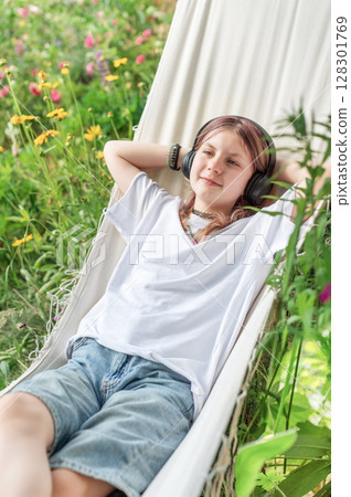 Relaxed teen listening to music in hammock 128301769