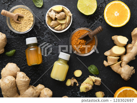 Bottles of immune turmeric ginger energy shot drink with fresh raw ginger roots and oranges fruits. Bottles of immune turmeric ginger energy shot drink with fresh raw ginger roots and oranges fruits. 128302697