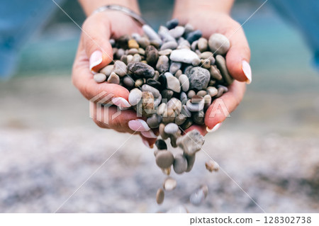 Hands Holding and Releasing Small Pebbles on the Beach Close-Up with Soft Natural Background Hands Holding and Releasing Small Pebbles on the Beach Close-Up with Soft Natural Background 128302738