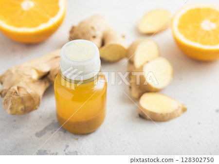 Turmeric energy shot immune drink with ginger root and ripe oranges on light background.Macro. 128302750