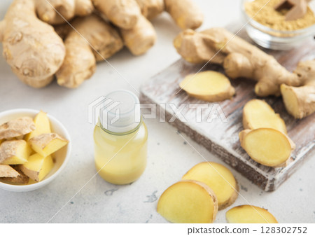 Immune ginger energy shot drink bottles with fresh raw ginger root on light background.Macro. 128302752