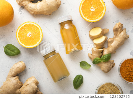 Bottles of immune ginger and orange energy shot drink with ginger root and turmeric powder. 128302755