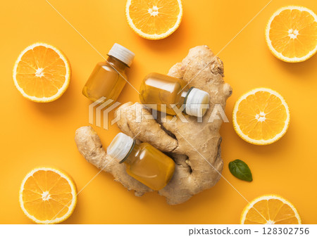Bottles of turmeric and orange energy immune shot drink with fresh oranges slices on orange. 128302756