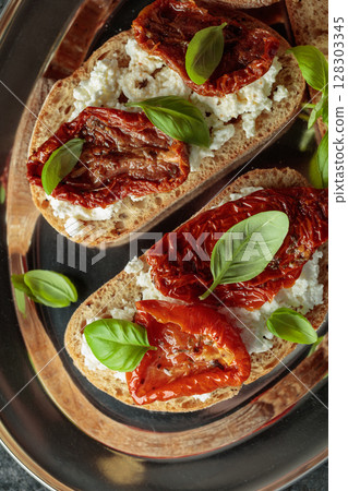 Ciabatta with sun dried tomatoes in olive oil, ricotta and basil. 128303345