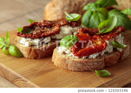 Ciabatta with sun dried tomatoes in olive oil, ricotta, and basil. 128303346