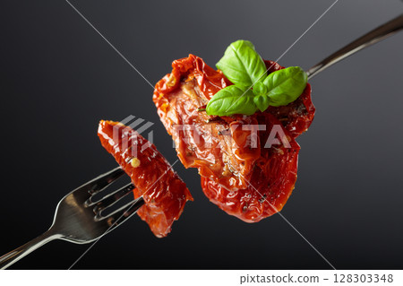 Sun dried tomatoes in olive oil with green basil. Sun dried tomatoes in olive oil with green basil. 128303348