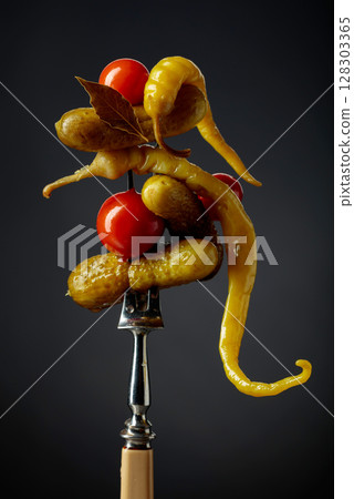 Canned yellow peppers, cucumbers, and tomatoes on a black background. 128303365