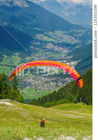 Colorful paraglider launching above Alpine valley, scenic summer mountain view. High quality photo Colorful paraglider launching above Alpine valley, scenic summer mountain view. High quality photo 128303399