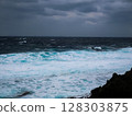 Rough coast with rough waves crashing against the rocks. Dramatic natural scenery on a cloudy day. 128303875