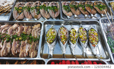 Marinated bangus or milkfish and marinated pork with vegetables displayed in trays ready for grilling in a street food stall showing a glimpse of the Philippines local cuisine and culture Marinated bangus or milkfish and marinated pork with vegetables displayed in trays ready for grilling in a street food stall showing a glimpse of the Philippines local cuisine and culture 128304462