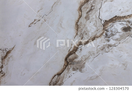 Elegant marble texture with intricate veins showcasing natural patterns in soft earth tones illuminated by ambient lighting 128304570