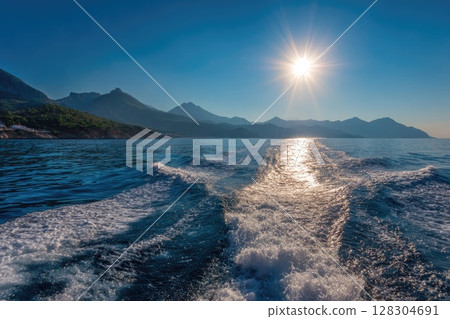 Realistic photo of the sea surface with a blue color and smooth waves, with the sun rising 128304691