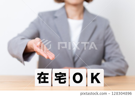 A middle-aged female business woman wearing a suit and a block saying "Work from home is OK" 128304896