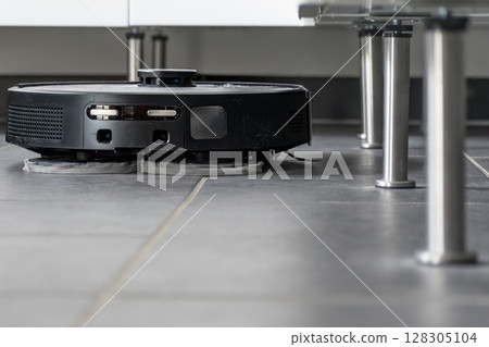 Robot vacuum cleaner with dust, real life photo, saves time and goes into hard-to-reach places 128305104