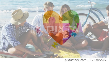 Image of colourful puzzle pieces heart over happy people on thebeach 128305507