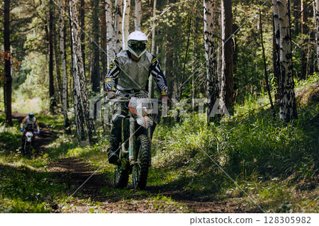 Two enduro rider biking muddy forest trail race Two enduro rider biking muddy forest trail race 128305982