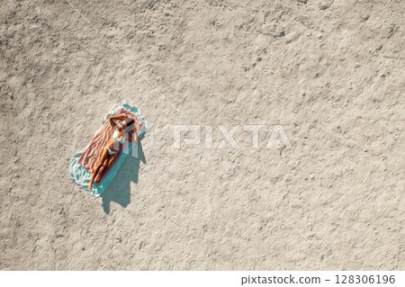 top view of a woman sunbathing on the beach top view of a woman sunbathing on the beach 128306196