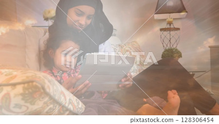 Image of asian mother in hijab with daughter over clouds Image of asian mother in hijab with daughter over clouds 128306454