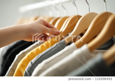 A woman hand is picking up t shirts from the rack 128306491