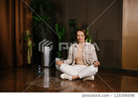 Woman Meditating In Office With Plants 128306896