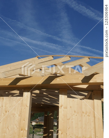 A wooden structure with a slanted roof is being built 128306964