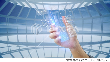 Holding futuristic transparent smartphone with digital interface in modern building 128307507