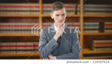 Businessman in suit thinking deeply in front of bookshelf in office 128307618