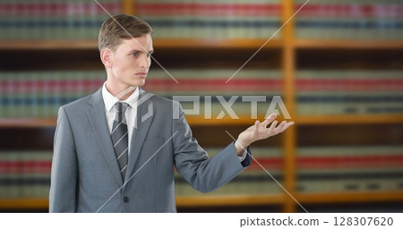 Young lawyer in suit presenting argument confidently in front of law books Young lawyer in suit presenting argument confidently in front of law books 128307620