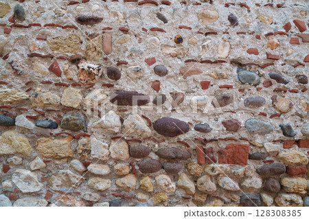 An old stone wall made of pebbles and bricks. Texture. Architecture. 128308385