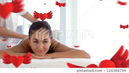 Masseuse doing massage to a beautiful relaxed women looking at camera at spa and red hearts with win Masseuse doing massage to a beautiful relaxed women looking at camera at spa and red hearts with win 128308794